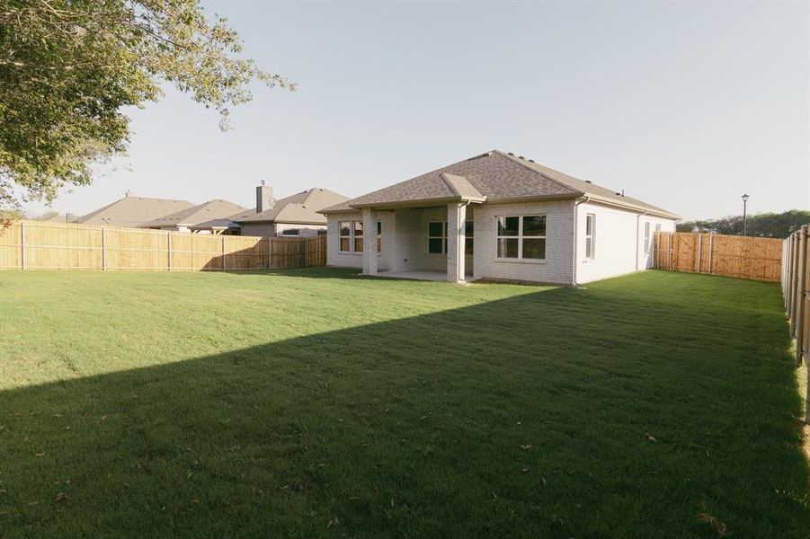 Rear view of house featuring a patio and a lawn