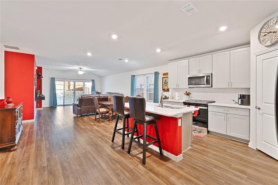 Kitchen with visible vents, light wood-type flooring, a sink, open floor plan, and appliances with stainless steel finishes