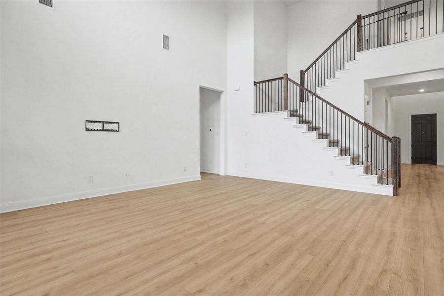Unfurnished living room featuring light wood-type flooring and a high ceiling