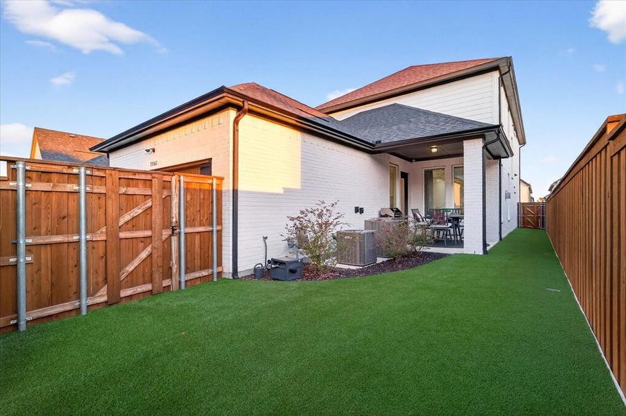 Back of property featuring a gate, a fenced backyard, brick siding, a patio, and a shingled roof Back of property featuring a gate, a fenced backyard, brick siding, a patio, and a shingled roof