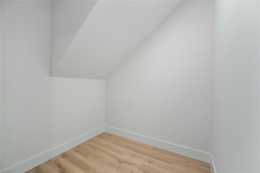 Additional living space featuring light wood-type flooring and lofted ceiling