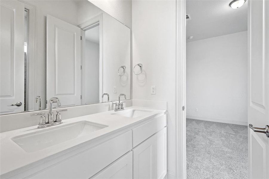 Full bath with double vanity and light carpet