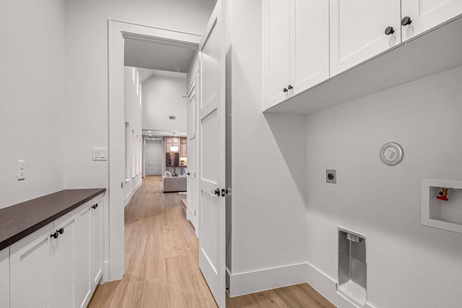 Laundry room featuring cabinet space, light wood finished floors, baseboards, hookup for an electric dryer, and washer hookup