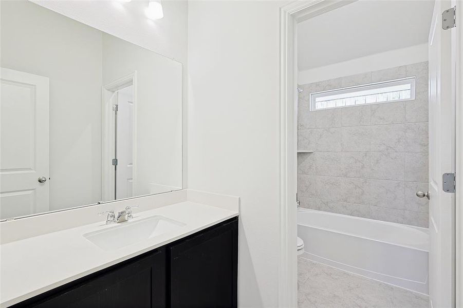 Full bathroom featuring tiled shower / bath, tile patterned floors, vanity, and toilet