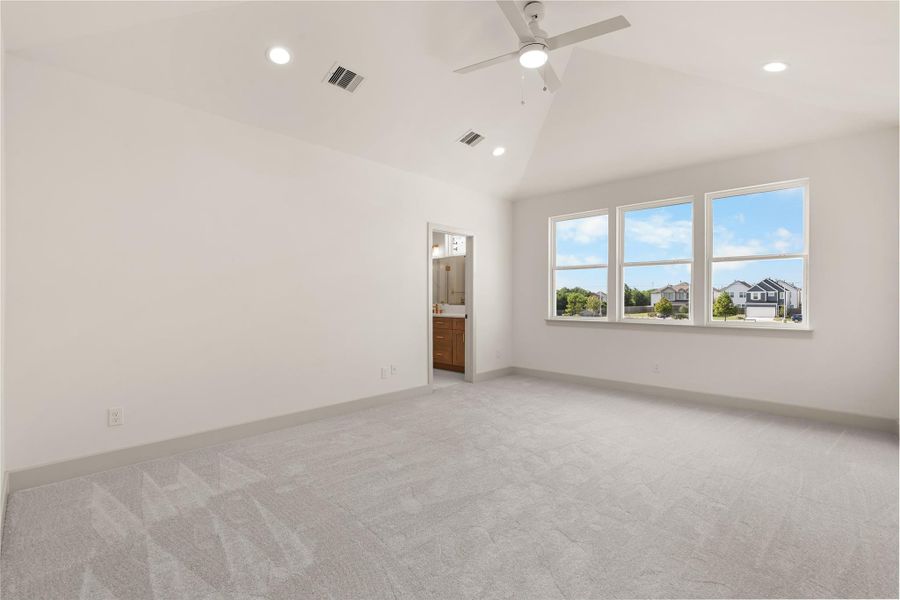 Primary suite — vaulted ceilings, plush carpet, triple windows, and en-suite access Primary suite — vaulted ceilings, plush carpet, triple windows, and en-suite access