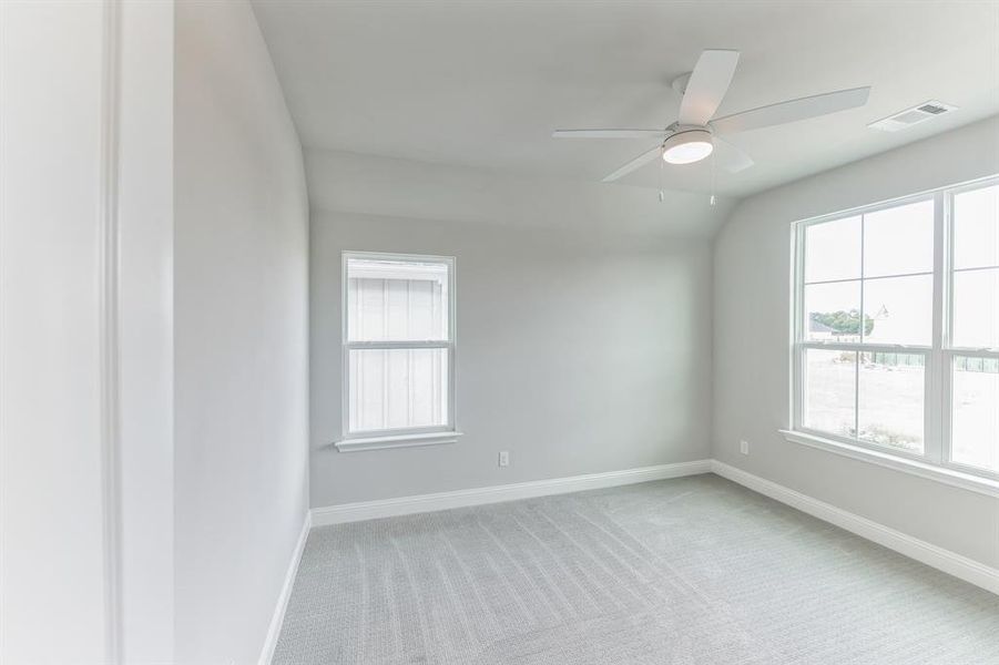 Carpeted empty room featuring lofted ceiling and ceiling fan