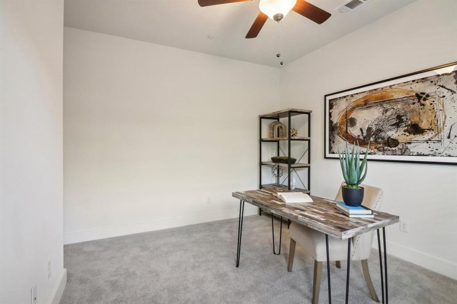 Home office with ceiling fan and light colored carpet