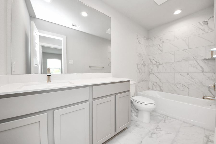 Secondary bath features tile flooring, bath/shower combo with tile surround, light stained wood cabinets, beautiful light countertop. Secondary bath features tile flooring, bath/shower combo with tile surround, light stained wood cabinets, beautiful light countertop.