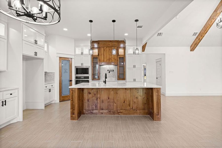 Kitchen featuring visible vents, appliances with stainless steel finishes, white cabinets, and backsplash