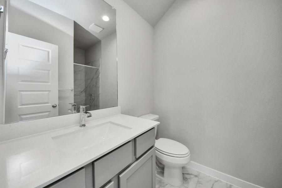 Guest suite bathroom, where tile flooring complements a walk-in shower with tile surround. Wood cabinets completed with a beautiful light countertop, enhances the space for a truly inviting ambiance. Sample photo of completed home with similar floor plan. Actual colors and selections may vary. Guest suite bathroom, where tile flooring complements a walk-in shower with tile surround. Wood cabinets completed with a beautiful light countertop, enhances the space for a truly inviting ambiance. Sample photo of completed home with similar floor plan. Actual colors and selections may vary.