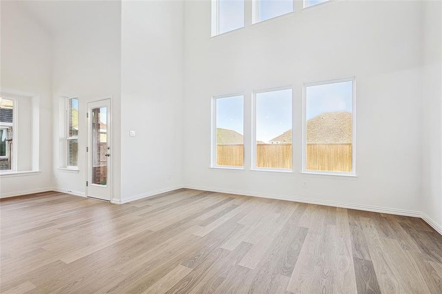 Unfurnished living room with a towering ceiling and light hardwood / wood-style flooring