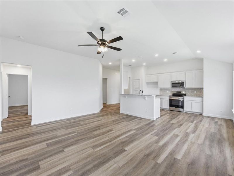 Open-concept living area with wood-finish flooring extending into the kitchen Open-concept living area with wood-finish flooring extending into the kitchen