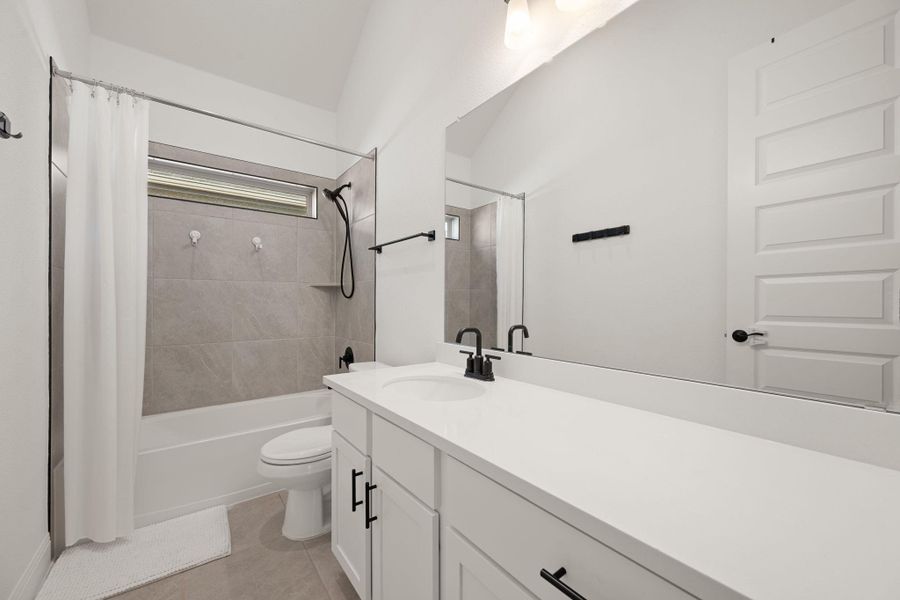 A well-lit primary bathroom featuring a clean vanity and a tiled shower-tub combination. A well-lit primary bathroom featuring a clean vanity and a tiled shower-tub combination.