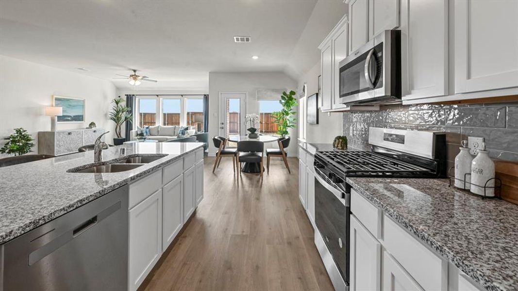 Kitchen featuring appliances with stainless steel finishes, white cabinetry, light stone countertops, recessed lighting, and dark wood-style flooring