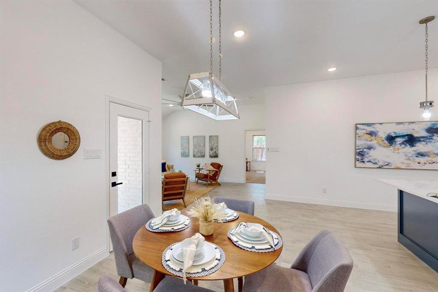 Dining room with light hardwood / wood-style flooring and high vaulted ceiling