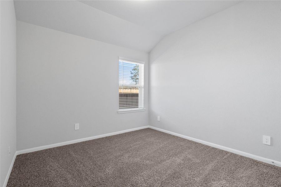 This cozy secondary bedroom offers plush soft carpeting, neutral walls ready for personalization, a sun-filled window with fitted blinds, sloped ceilings, and a spacious closet for all your storage needs.