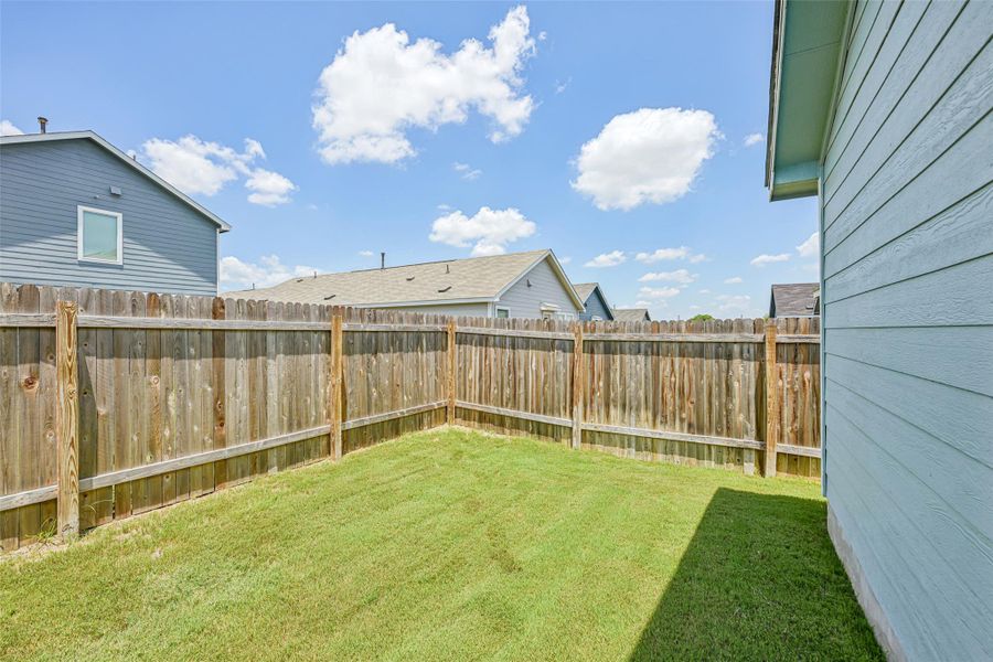Fenced backyard featuring a manicured lawn, wood privacy fencing, and light blue siding on the exterior Fenced backyard featuring a manicured lawn, wood privacy fencing, and light blue siding on the exterior
