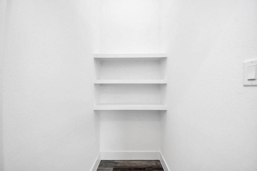 Compact storage space featuring three white shelves, ideal for organizing essentials. The area is well-lit with a light switch conveniently located on the wall. Compact storage space featuring three white shelves, ideal for organizing essentials. The area is well-lit with a light switch conveniently located on the wall.