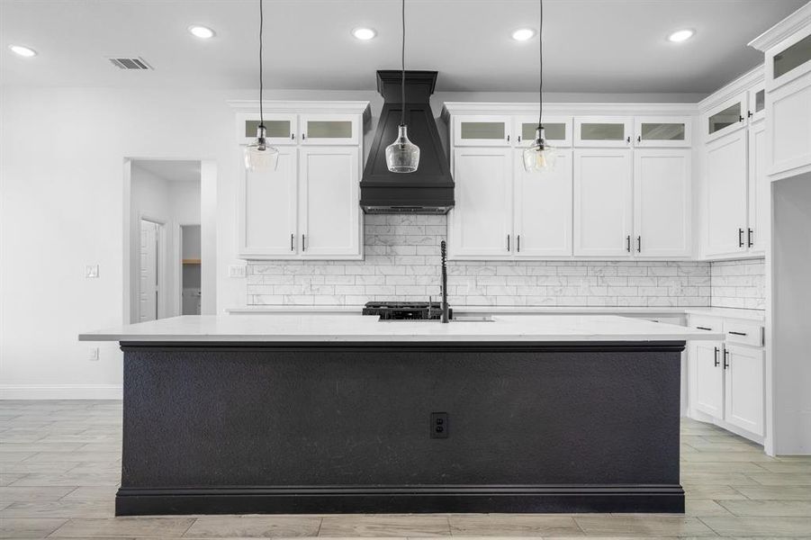 Kitchen featuring white cabinetry, a kitchen island with sink, pendant lighting, and premium range hood