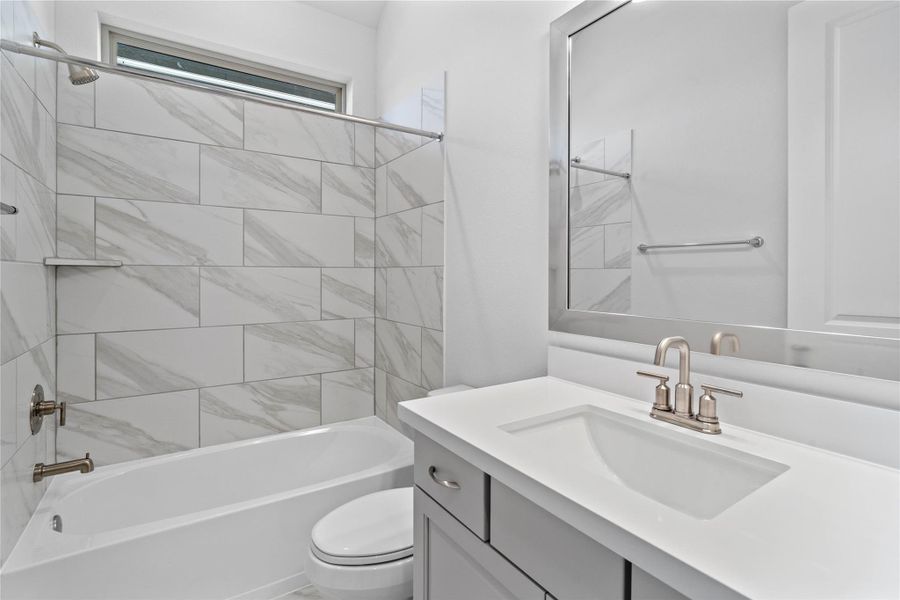 This well-appointed secondary bathroom features a sleek single vanity with a crisp white countertop and modern fixtures, set against a stunning gray and white marble-look tile in the tub/shower combination. This well-appointed secondary bathroom features a sleek single vanity with a crisp white countertop and modern fixtures, set against a stunning gray and white marble-look tile in the tub/shower combination.