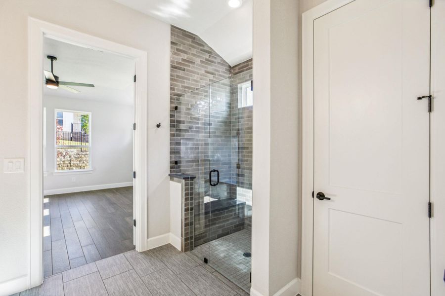 Full bathroom featuring healthy amount of natural light, vaulted ceiling, wood finish floors, a shower stall, and ceiling fan Full bathroom featuring healthy amount of natural light, vaulted ceiling, wood finish floors, a shower stall, and ceiling fan