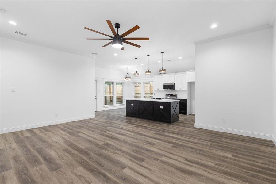 Unfurnished living room with dark hardwood / wood-style flooring, sink, ceiling fan, and crown molding