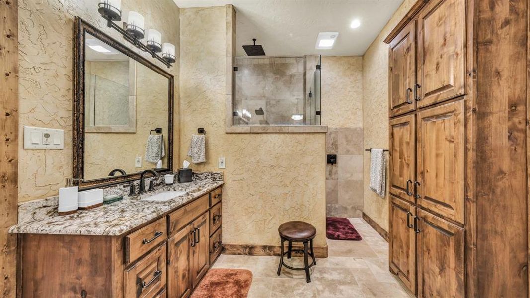 Walk-in shower with glass enclosure, dual shower heads, and abundant cabinet storage.
