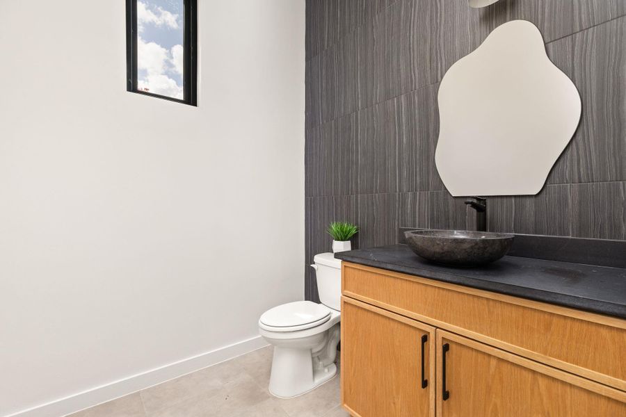 Modern bathroom featuring a stylish vessel sink and a striking dark tile accent wall.