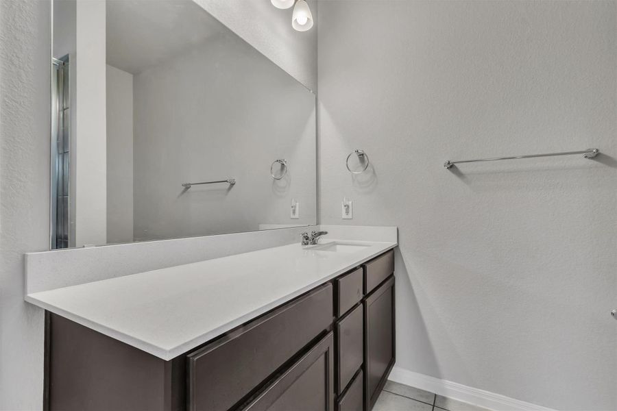 A well-appointed bathroom features a dark wood vanity, white countertop, and a wide mirror.