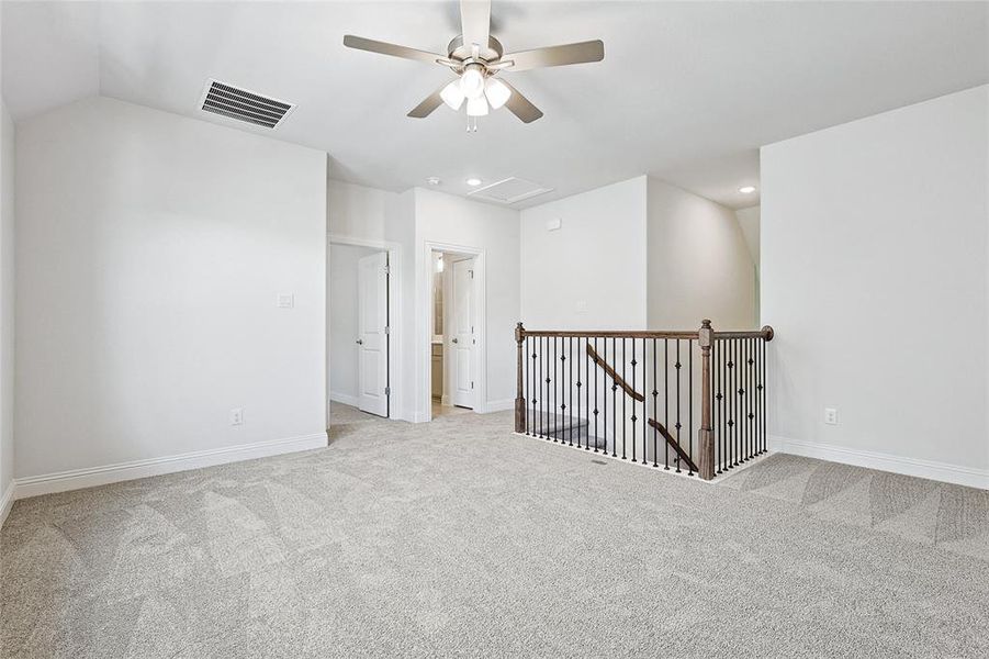 Carpeted empty room featuring vaulted ceiling and ceiling fan