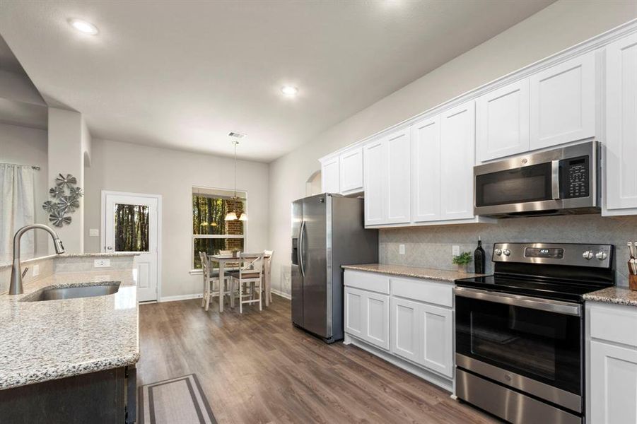 Light and bright kitchen with sleek white kitchen cabinets, stainless steel appliances, and granite countertops.