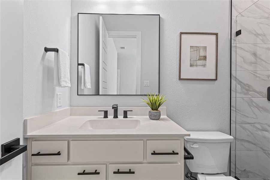 Full bathroom featuring a textured wall, vanity, and a shower stall