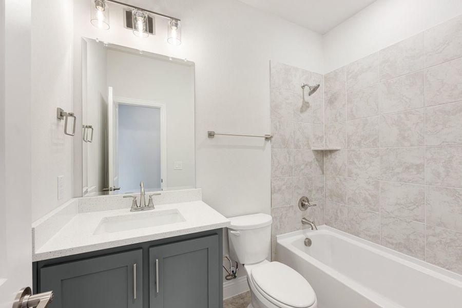Bathroom with gray vanity, white quartz countertop, and tiled tub-shower combo Bathroom with gray vanity, white quartz countertop, and tiled tub-shower combo