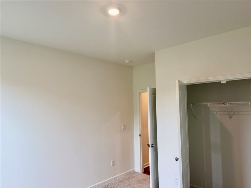 A quiet bedroom features soft wall-to-wall carpeti