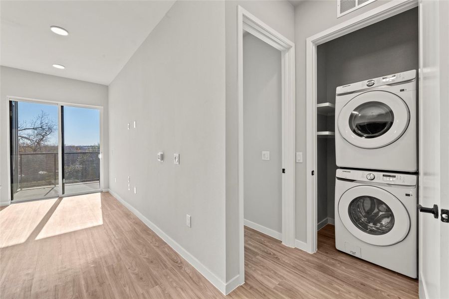 Clothes washing area featuring stacked washer / drying machine and light hardwood / wood-style flooring