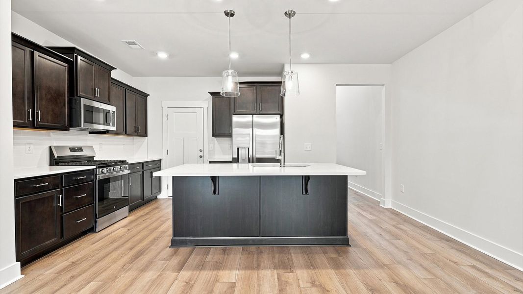 Superior craftsmanship shines in this modern kitchen with a space-saving island and open flow at Village at Midway