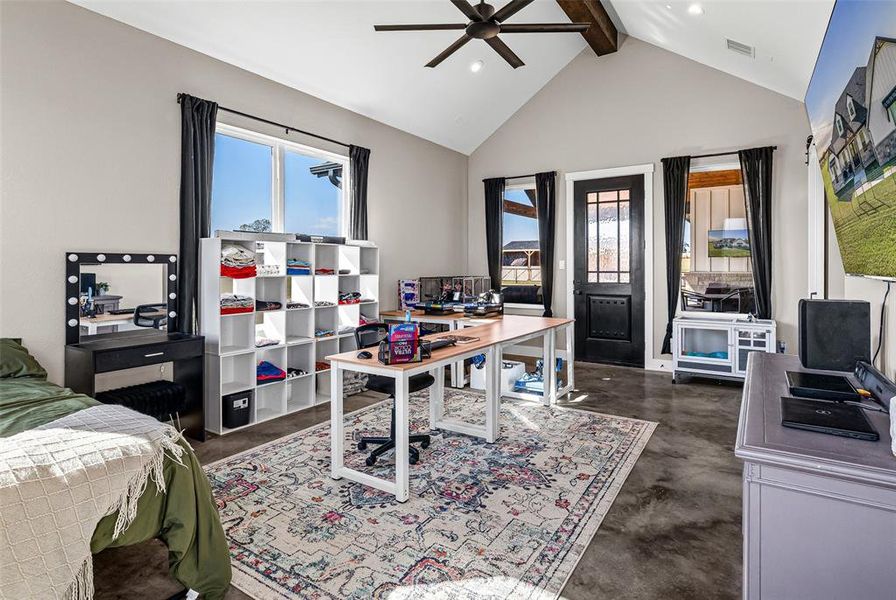 Bedroom featuring a desk, beam ceiling, ceiling fan, high vaulted ceiling, and finished concrete flooring Bedroom featuring a desk, beam ceiling, ceiling fan, high vaulted ceiling, and finished concrete flooring
