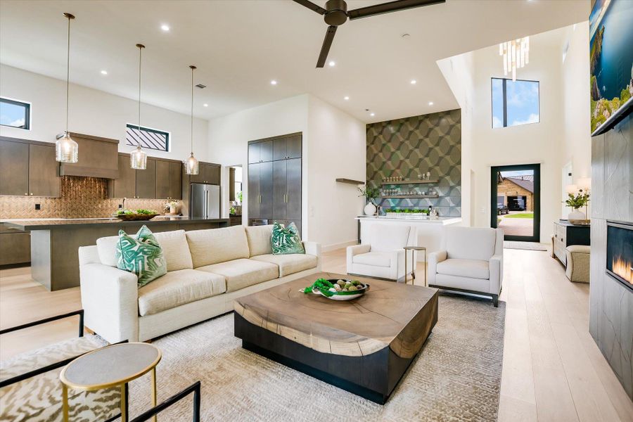 An open-concept living area with a captivating fireplace and high ceilings connects to a modern kitchen.