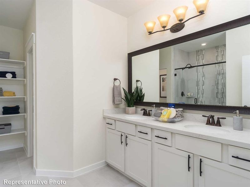 Full bath featuring double vanity, a shower stall, and light tile patterned flooring