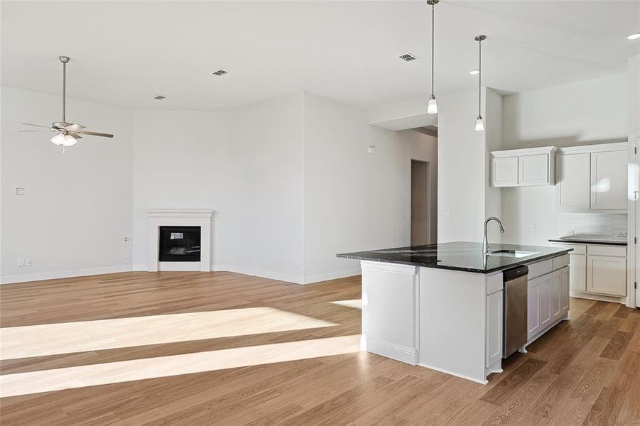 Kitchen featuring a kitchen island with sink, light wood-type flooring, white cabinetry, and ceiling fan