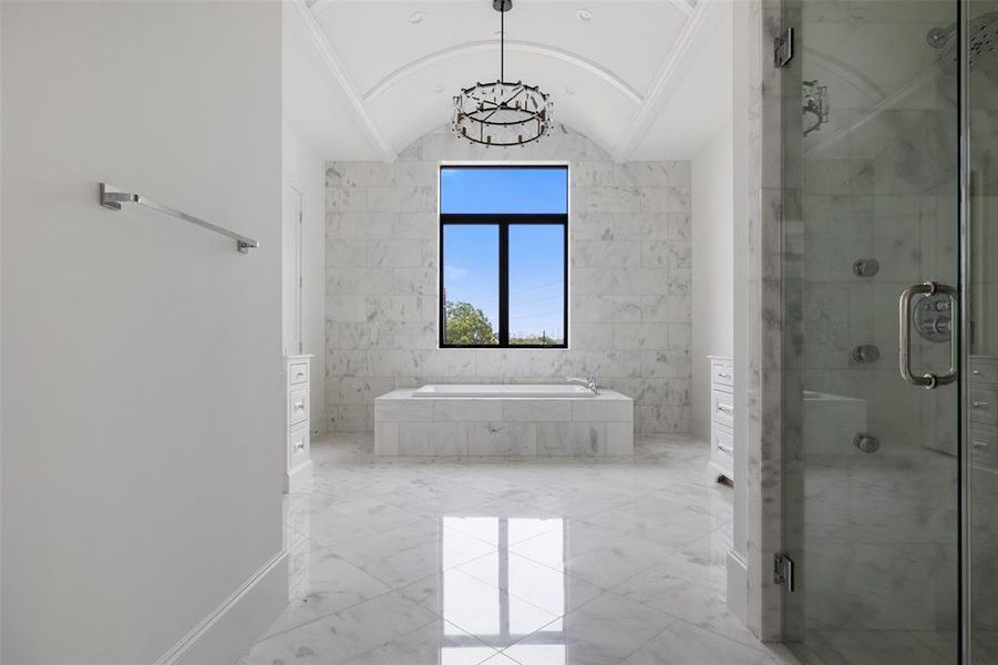 The standout features of the primary spa-suite include extensive marble cladding and a stunning barrel vault ceiling with designer chandelier. Image from previously completed home in the community.