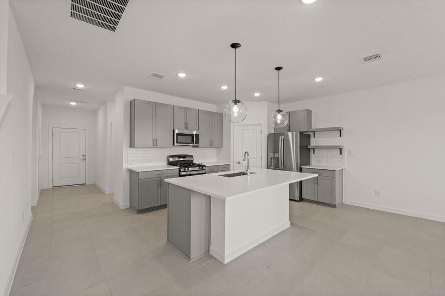 Island kitchen with grey cabinets and quartz countertops