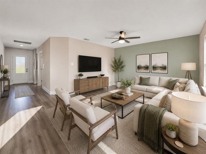 Spacious living area featuring wood-finish flooring, a ceiling fan, and a light green accent wall