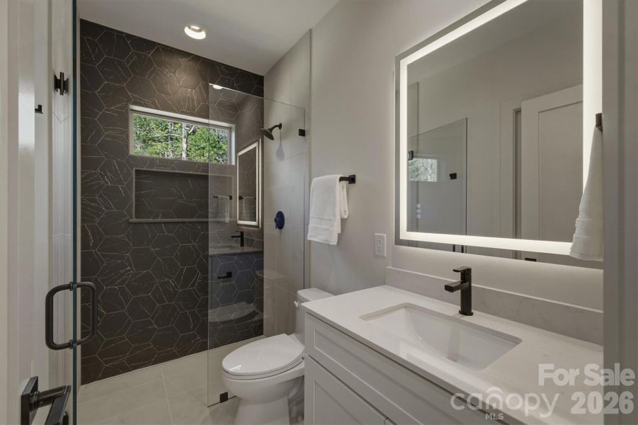 Next, this bathroom can be accessed from the hall or from Bedroom Suite #2. There is a custom tiled zero entry shower with its custom glass door, a quartz counter top for the vanity and a great lighted mirror. Next, this bathroom can be accessed from the hall or from Bedroom Suite #2. There is a custom tiled zero entry shower with its custom glass door, a quartz counter top for the vanity and a great lighted mirror.