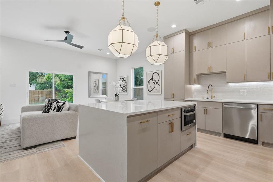 Open-concept living space featuring light wood-finish flooring, a kitchen island with a built-in microwave, stainless steel dishwasher, and recessed lighting Open-concept living space featuring light wood-finish flooring, a kitchen island with a built-in microwave, stainless steel dishwasher, and recessed lighting