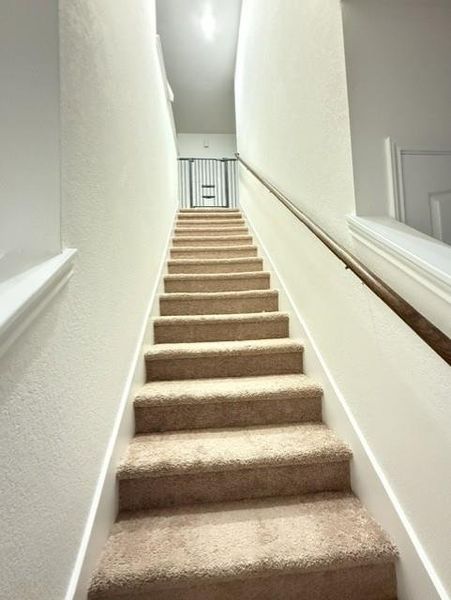Carpeted staircase with wood handrail leading to the spacious second floor. Carpeted staircase with wood handrail leading to the spacious second floor.