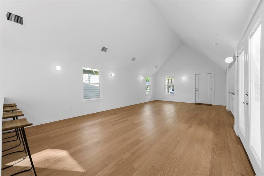 Unfurnished living room featuring high vaulted ceiling and light wood-type flooring