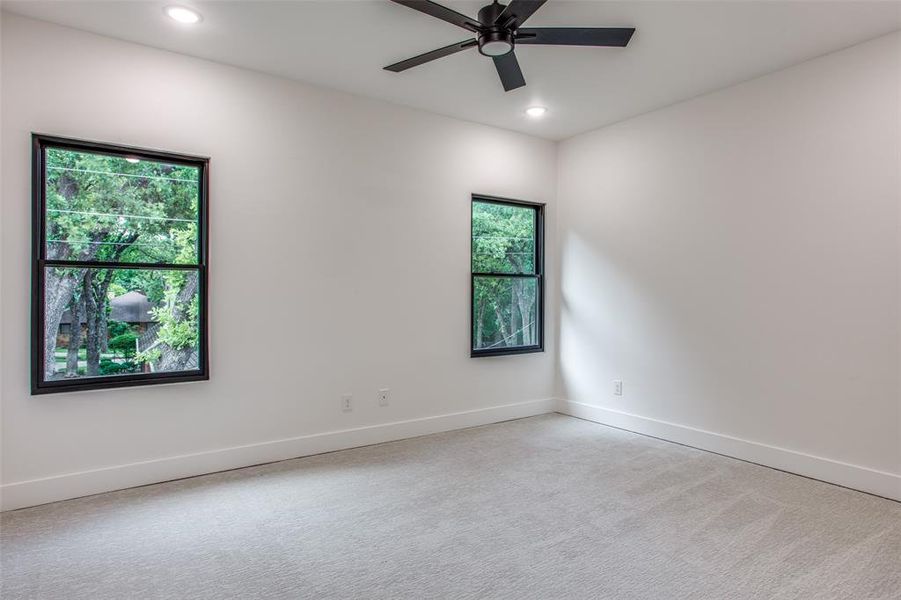 Spare room with ceiling fan, plenty of natural light, and light carpet