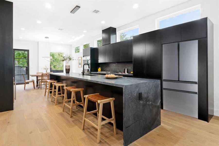 Striking kitchen with leathered, black, marble countertops. *fridge is a rendering but one will be installed*