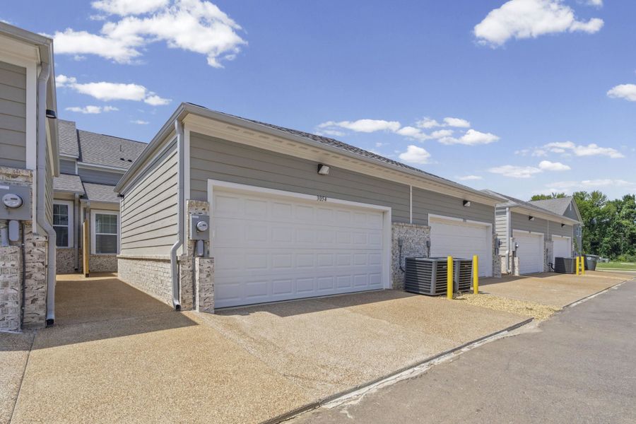 Multiple attached garages featuring white doors and light gray siding with stone veneer accents